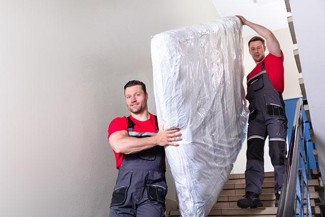 two people carrying a box spring down a staircase in Emerald Isle