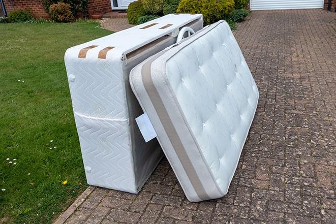 a mattress being carefully carried out of a home for disposal